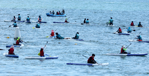 ‘제12회 대한민국 국제해양레저위크’가 부산 수영구 광안리해수욕장 일원에서 열리고 있는 가운데 12일 해양레저 체험에 참가한 학생들이 패들보드를 체험하고 있다. 2024.8.12. 연합뉴스