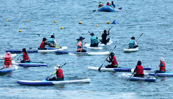‘제12회 대한민국 국제해양레저위크’가 부산 수영구 광안리해수욕장 일원에서 열리고 있는 가운데 12일 해양레저 체험에 참가한 학생들이 패들보드를 체험하고 있다. 2024.8.12. 연합뉴스