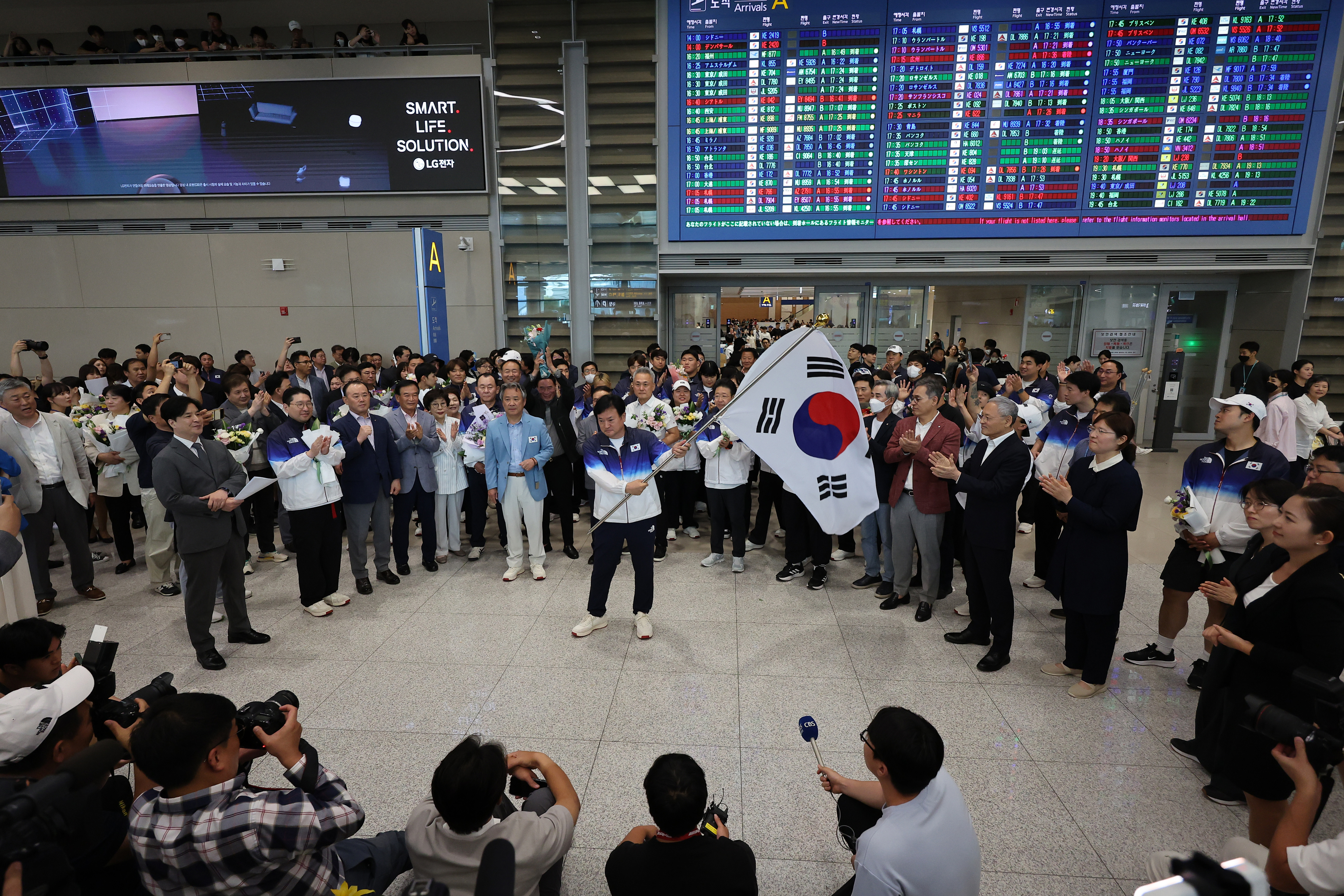 정강선 파리 올림픽 대한민국 선수단장이 13일 오후 인천국제공항 제2여객터미널을 통해 귀국해 태극기를 휘날리고 있다. 연합뉴스