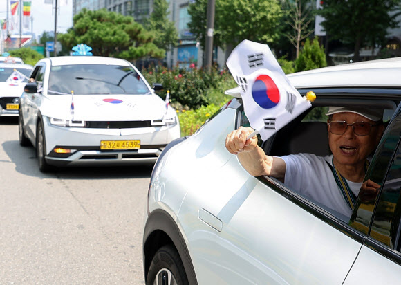 송파구청이 송파모범운전자회와 함께 13일 오전 서울 송파구 올림픽공원 인근에서 개최한 ‘호국영웅택시 카퍼레이드’에서 한 참가자가 태극기를 흔들고 있다. 2024.8.13. 연합뉴스