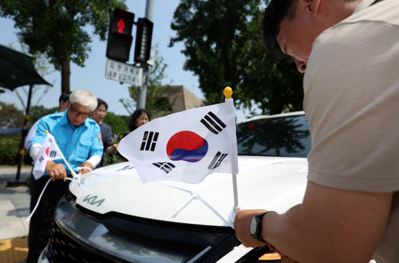 송파구청이 송파모범운전자회와 함께 13일 오전 서울 송파구 올림픽공원 인근에서 연 ‘호국영웅택시 카퍼레이드’에서 참가자들이 태극기를 택시에 부착하고 있다. 2024.8.13. 연합뉴스