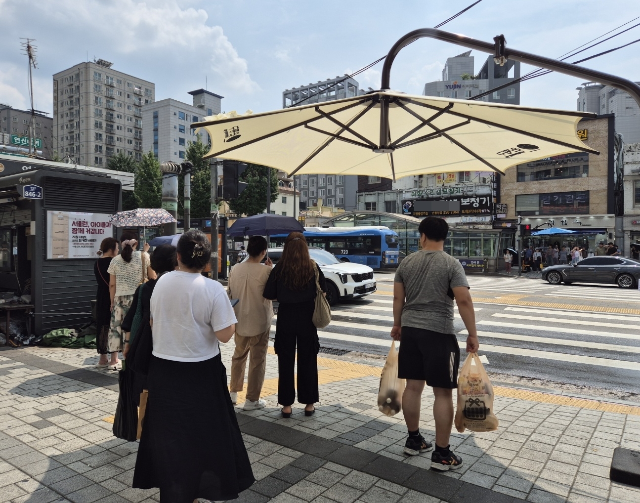 11일 서울 은평구 연신내역 앞 사거리에서 시민들이 그늘막 아래 모여 횡단보도 신호를 기다리고 있다. 송현주 기자