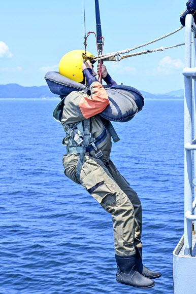 공군이 지난 14일 경남 해상생환훈련장에서 조종사 해상생환훈련을 실시했다고 17일 밝혔다. 사진은 김준태 연합뉴스 기자가 낙하산 견인 훈련을 위해 훈련용 배 후미에 매달려 있는 모습. 2024.8.17  공군 제공