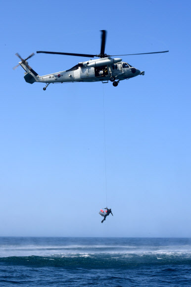 해군1함대사령부 6구조작전중대 소속 심해잠수사가 19일 강원도 동해 군항 인근 해상에서 해상 조난자 구조를 위해 헬기에서 구조용 인양장치를 이용해 해상으로 강하하고 있다. 2024.8.19. 해군 제공