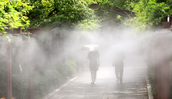 전국 대부분 지역에 폭염특보가 발효된 가운데 절기상 ‘처서’를 맞은 22일 대구 중구 국채보상운동기념공원에 설치된 쿨링포그(안개형 냉각수) 아래로 시민들이 더위를 식히며 이동하고 있다. 2024.8.22 연합뉴스