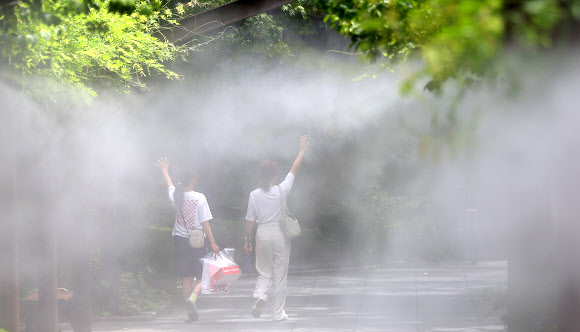전국 대부분 지역에 폭염특보가 발효된 가운데 절기상 ‘처서’를 맞은 22일 대구 중구 국채보상운동기념공원에 설치된 쿨링포그(안개형 냉각수) 아래로 시민들이 더위를 식히며 이동하고 있다. 2024.8.22 연합뉴스