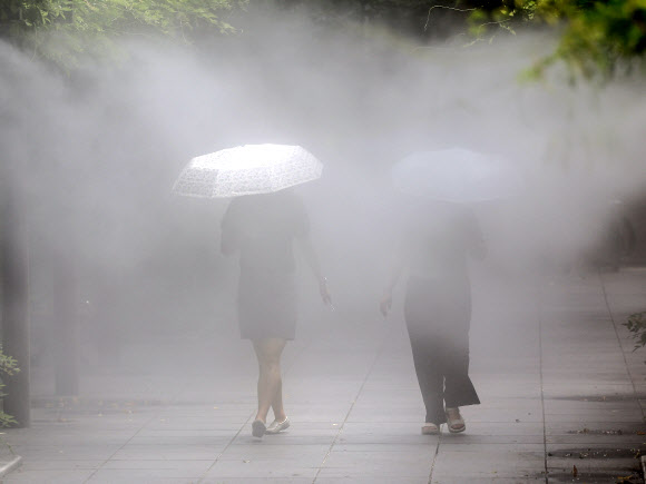 전국 대부분 지역에 폭염특보가 발효된 가운데 절기상 ‘처서’를 맞은 22일 대구 중구 국채보상운동기념공원에 설치된 쿨링포그(안개형 냉각수) 아래로 시민들이 더위를 식히며 이동하고 있다. 2024.8.22 연합뉴스