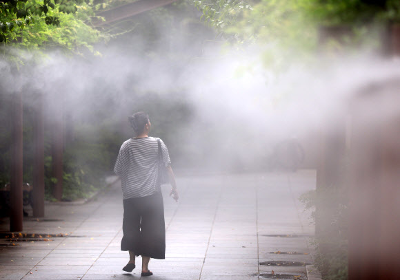 전국 대부분 지역에 폭염특보가 발효된 가운데 절기상 ‘처서’를 맞은 22일 대구 중구 국채보상운동기념공원에 설치된 쿨링포그(안개형 냉각수) 아래로 시민들이 더위를 식히며 이동하고 있다. 2024.8.22 연합뉴스