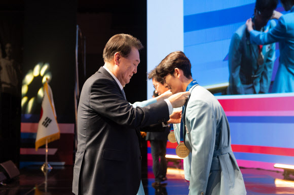 윤석열 대통령과 김건희 여사가 22일 서울 중구 신라호텔에서 열린 ‘2024 파리올림픽 선수단 격려 행사’에서 스포츠클라이밍 스피드 종목에 출전한 신은철 선수(오른쪽), 근대5종 동메달을 획득한 성승민 선수를 지도한 김성진 코치에게 직접 메달을 수여하고 있다.   2024.8.22. 대통령실 제공