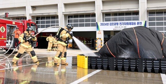 23일 서울 강서구 김포공항 항공기 이동지역에서 열린 한국공항공사 전기차 화재 소방 훈련에서 공항소방대가 화재 차량의 하부 배터리 설치 높이까지 물을 채우고 있다. 2024.8.23. 한국공항공사 제공