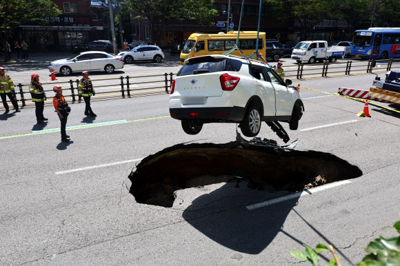 29일 오전 서울 서대문구 연희동 성산로에서 발생한 땅 꺼짐 사고로 빠져버린 승용차가 크레인으로 옮겨지고 있다. 2024.8.29  연합뉴스