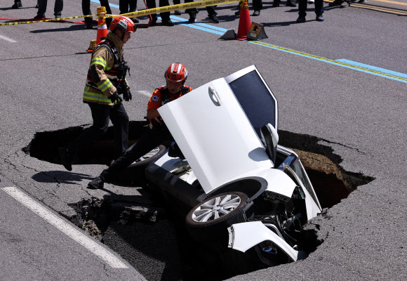 29일 오전 서울 서대문구 연희동 성산로에서 발생한 땅 꺼짐 사고 현장에서 소방 관계자들이 사고 차량을 살펴보고 있다. 2024.8.29  연합뉴스