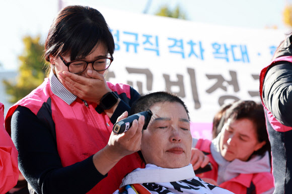민주노총 서비스연맹 전국학교비정규직노동조합 조합원들이 6일 오전 서울 용산구 대통령실 인근에서 정부의 비정규직 임금 격차·학교급식실 결원·노동자 안전권 방치 등을 규탄하며 삭발식을 연 가운데 이발기로 조합원 삭발을 돕는 조합원이 눈물을 흘리고 있다. 2024.11.6 연합뉴스