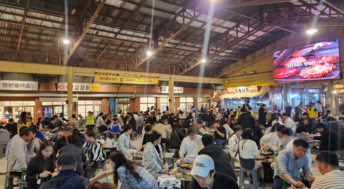 전국에서 찾아온 방문객들이 예산시장 푸드코트에 앉아 백종원 가게 음식을 즐기고 있다.