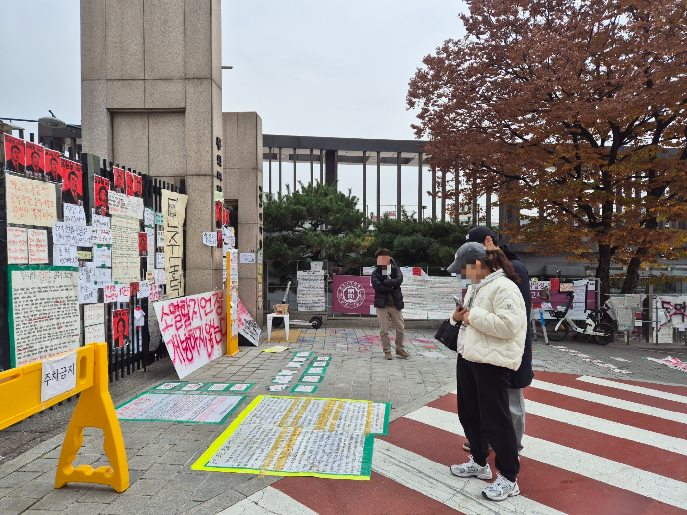 신남성연대의 ‘동덕여대 공학 전환 환영 및 페미니즘 규탄 집회’가 취소된 지난 20일 정오쯤 서울 성북구 동덕여대 앞을 지나가던 시민들이 학생들이 바닥에 붙인 대자보를 읽어보고 있다. 송현주 기자