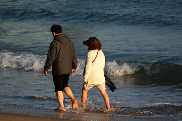 서울을 비롯한 전국 대부분 지역에 폭설이 내린 28일 오후 부산 수영구 광안리해수욕장에서는 시민들이 해변 맨발 걷기를 하고 있다. 이날 부산은 한낮 기온이 10도 안팎을 기록했다. 2024.11.28. 연합뉴스