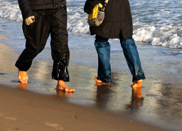 서울을 비롯한 전국 대부분 지역에 폭설이 내린 28일 오후 부산 수영구 광안리해수욕장에서는 시민들이 해변 맨발 걷기를 하고 있다. 이날 부산은 한낮 기온이 10도 안팎을 기록했다. 2024.11.28. 연합뉴스