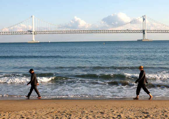 서울을 비롯한 전국 대부분 지역에 폭설이 내린 28일 오후 부산 수영구 광안리해수욕장에서는 시민들이 해변 맨발 걷기를 하고 있다. 이날 부산은 한낮 기온이 10도 안팎을 기록했다. 2024.11.28. 연합뉴스