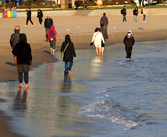서울을 비롯한 전국 대부분 지역에 폭설이 내린 28일 오후 부산 수영구 광안리해수욕장에서는 시민들이 해변 맨발 걷기를 하고 있다. 이날 부산은 한낮 기온이 10도 안팎을 기록했다. 2024.11.28. 연합뉴스
