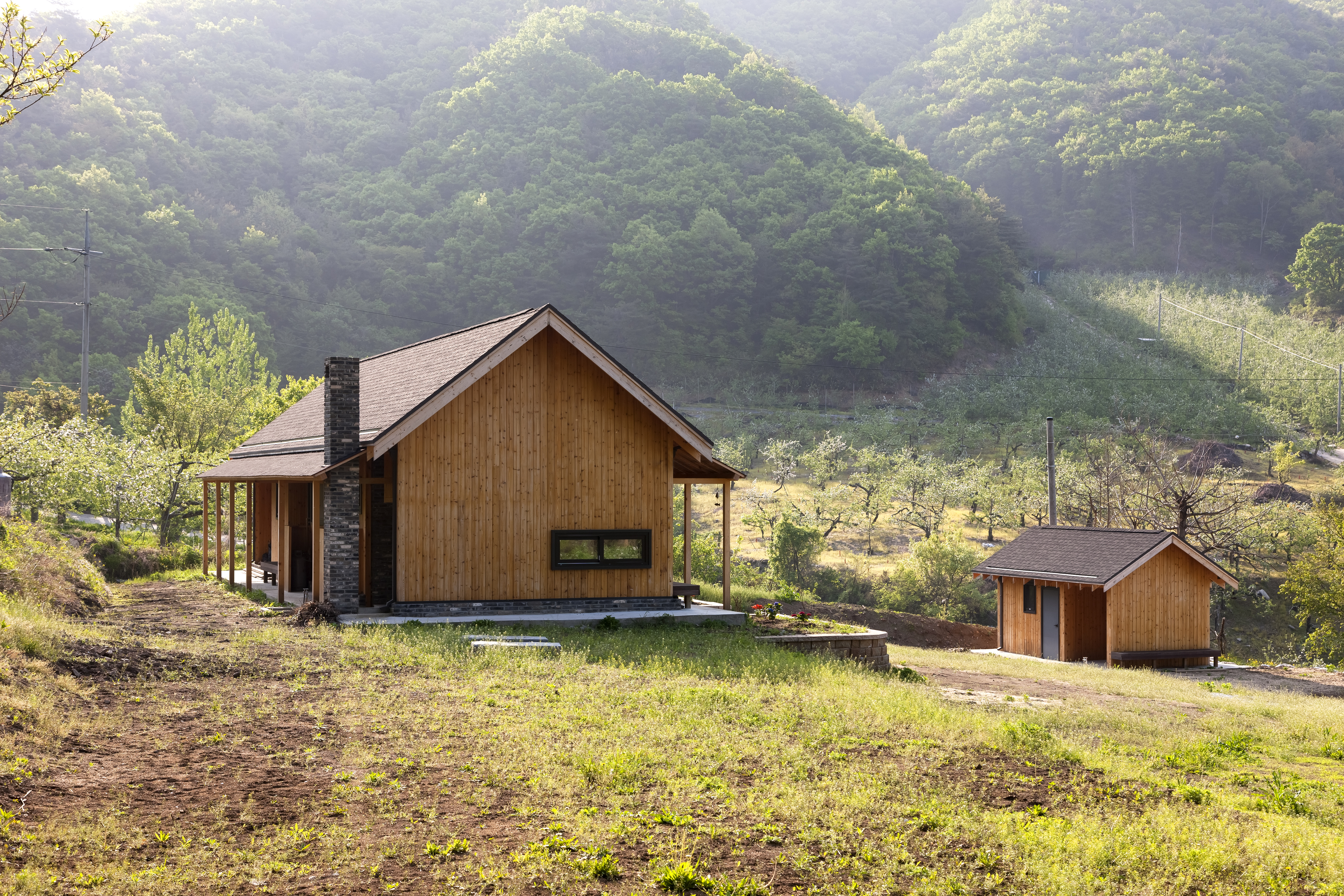 산을 좋아해 산 가까이에 자연과 어울리는 삶을 담아낸 ‘자기 앞의 집’. 옛 대청과 같은 역할을 하는 거실과 부엌을 넣고 양쪽 끝에 안방과 다실을 겸한 손님방을 두었다. 좌식으로 사용할 다실에는 앉았을 때 비로소 보이는 낮은 창을 냈고 담 대신 대문채를 두어 집의 영역을 암시했다.  박영채 제공