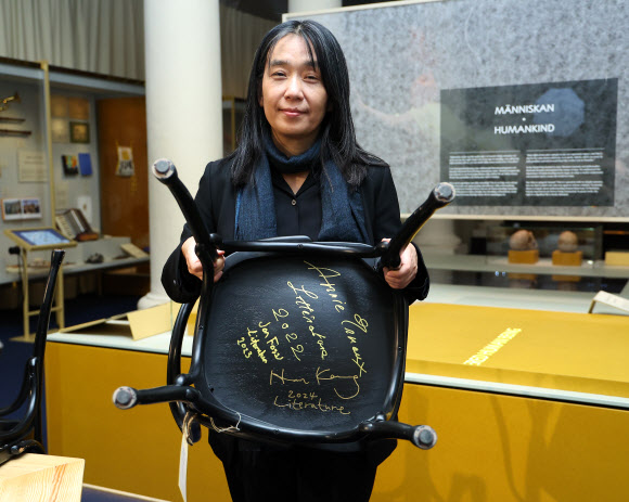 2024 노벨문학상 수상자인 한강 작가가 6일(현지시간) 스웨덴 스톡홀름 노벨박물관에서 수상자만을 위한 특별한 방명록인 박물관 레스토랑 의자에 서명을 남긴 뒤 의자를 들고 포즈를 취하고 있다. 2024.12.6  연합뉴스