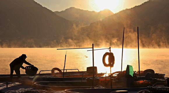 10일 오전 강원 인제군 소양호 일원에 물안개가 피어오른 가운데 한 어부가 아침 조업을 마치고 어획 도구를 정리하고 있다. 2024.12.10. 인제군 제공