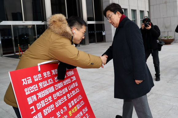 국민의힘 권성동 신임 원내대표가 13일 오전 국회 본청 앞에서 탄핵 찬성을 호소하는 김상욱 의원과 악수하고 있다. 2024.12.13  연합뉴스