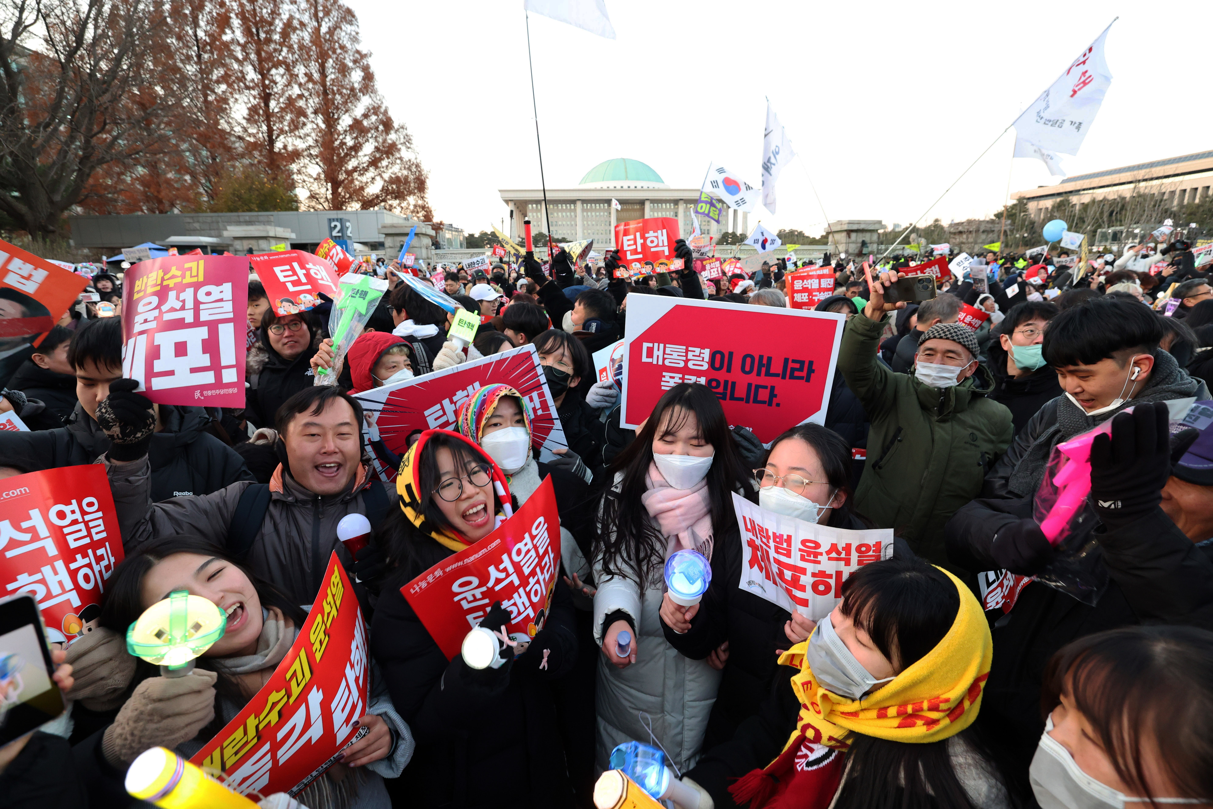 윤석열 대통령 탄핵소추안이 가결된 지난 14일 서울 여의도 국회의사당 앞에 모인 시민들이 ‘윤석열을 탄핵하라’ 등의 피켓을 든 채 환호하고 있다.