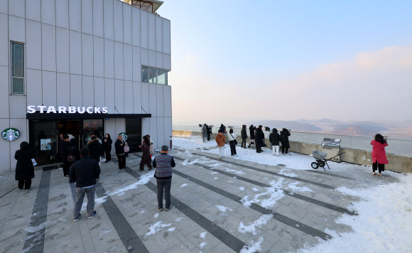 21일 오후 경기 김포시 애기봉 평화생태공원 조강전망대를 찾은 시민들이 스타벅스 김포애기봉 생태공원점 앞에서 북한 황해도 개풍군을 바라보고 있다.  이 스타벅스는 북한과 불과 1.4㎞ 떨어진 비무장지대(DMZ)인 애기봉에 지난달 29일 문을 열었다. 2024.12.21  연합뉴스