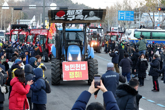22일 오후 서울 서초구 남태령에서 열린 ‘윤석열 대통령 체포·구속 농민 행진 보장 촉구 시민대회’에서 트랙터와 시민들이 경찰 버스를 지나 한남동 대통령 관저 방향으로 행진하고 있다. 2024.12.22  연합뉴스