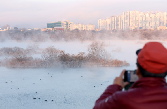 강원 내륙과 산지 곳곳의 아침 최저기온이 영하 10도 아래로 뚝 떨어진 23일 춘천시 소양강에서 한 시민이 짙은 물안개가 핀 풍경을 사진 찍고 있다. 2024.12.23. 연합뉴스