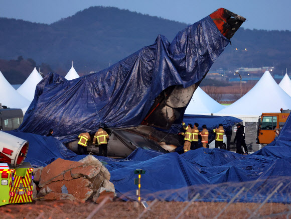 제주항공 여객기 참사 7일째인 4일 오후 수색 작업이 끝난 무안국제공항 사고 현장에서 소방대원들이 꼬리 날개에 방수포를 덮고 있다. 2025.1.4. 연합뉴스
