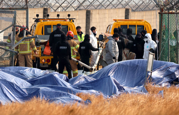 제주항공 여객기 참사 9일째인 6일 오전 전남 무안공항에서 경찰특공대원과 소방대원들이 울타리 밖에 있던 기체 잔해를 옮기고 있다. 2025.1.6. 연합뉴스