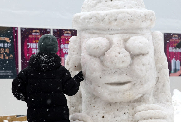 눈이 내린 31일 오후 서울 중구 서울광장 인근에 놓인 눈으로 만들어진 돌하르방 조각을 한 아이가 살피고 있다. 2025.1.31 연합뉴스