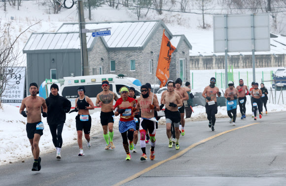 1일 강원 평창군 대관령에 열린 ‘2025 평창 대관령 알몸 마라톤 대회’ 참가자들이 눈 쌓인 대관령 일원의 도로를 달리고 있다.  이 대회는 남자는 상의 탈의, 여성은 민소매나 반소매 티를 입어야 하는 복장 규정이 있다. 2025.2.1  연합뉴스