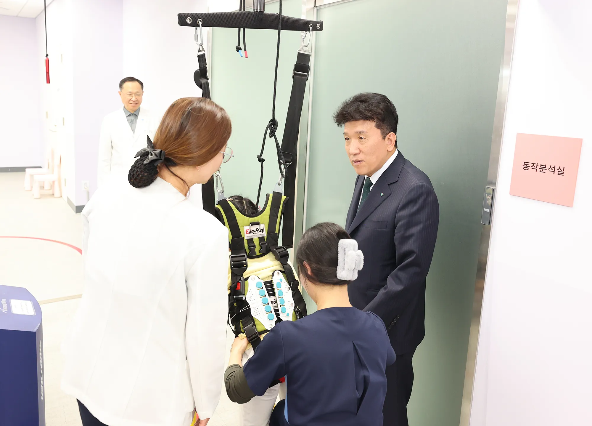 함영주 하나금융지주 회장(맨 오른쪽)이 17일 서울 마포구 푸르메재단 넥슨어린이재활병원에서 워킹레일 보행치료를 받고 있는 장애아동을 격려하고 있다. 하나금융지주 제공