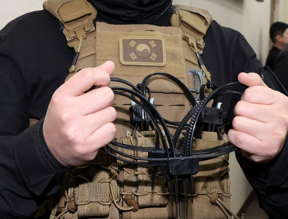 20일 서울 여의도 국회에서 열린 국방위원회 전체회의에 군복장을 한 더불어민주당 박선원 의원의 수석보좌관이 케이블타이 수갑을 들어보이고 있다. 2025.2.20. 연합뉴스