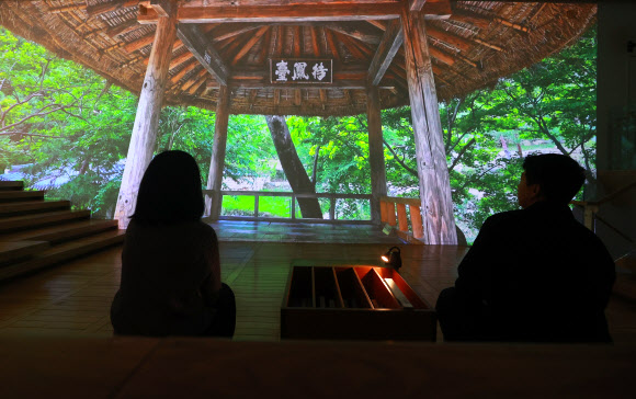 24일 오전 서울 종로구 세종문화회관 미술관에서 열린 ‘미음완보(微吟緩步), 전통 정원을 거닐다’ 전시 언론공개회에서 참석자들이 미디어 아트 영상을 관람하고 있다.  이번 전시는 국가유산청이 2021년부터 전통 조경을 정밀 실측·조사하며 축적해 온 데이터를 활용해 옛사람들이 꾸민 정원과 자연경관을 디지털 기술로 생생하게 구현했다. 2025.2.24. 연합뉴스