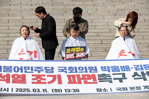 11일 서울 여의도 국회 본청 앞 계단에서 더불어민주당 전진숙(왼쪽부터), 박홍배, 김문수 의원이 윤석열 대통령 조기파면 등을 촉구하며 삭발하고 있다. 2025.3.11  연합뉴스