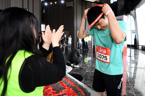 20일 서울 송파구 롯데월드타워에서 열린 ‘2025 롯데월드타워 스카이런 위드 스파이더(SPYDER)’에서 한 참가자가 결승점을 통과한 뒤 메달을 목에 걸고 있다. 2025.4.20. 연합뉴스