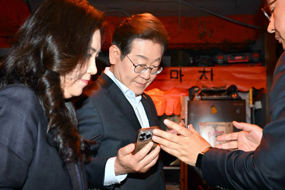 더불어민주당 이재명 대선 후보가 1일 서울 종로구의 한 포차 식당에서 ‘당신의 하루를 만드는, 보이지 않는 영웅들’이란 주제로 배달 라이더, 택배 기사 등 비(非)전형 노동자들과 간담회를 마친 뒤 휴대전화를 확인하고 있다. 2025.5.1 공동취재