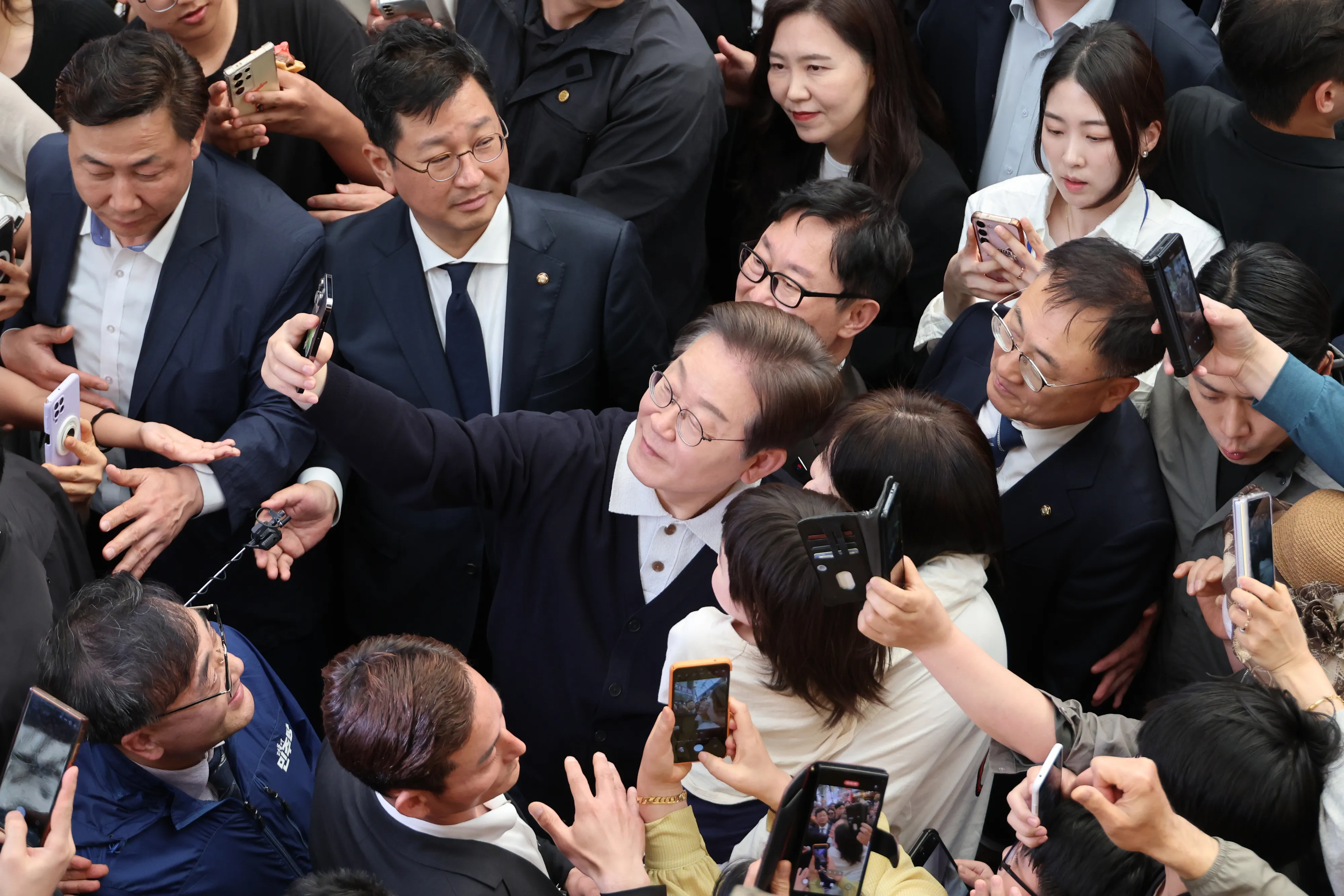 단양팔경에서 ‘경청 투어’ 이어가는 이재명 후보  이재명(가운데) 더불어민주당 대선후보가 ‘골목골목 경청 투어’ : 단양팔경 편‘에 나선 4일 충북 단양군 단양구경시장에서 한 아이를 안은 가족과 사진을 찍어주고 있다. 2025.5.4