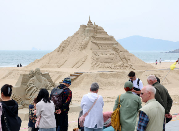 11일 오후 부산 해운대해수욕장에서 외국인관광객과 시민들이 모래 작품을 감상하고 있다. 올해로 20주년을 맞는 부산 해운대 모래 축제는 16일부터 19일까지 ‘모래로 만나는 K-컬쳐’를 주제로 열린다.  연합뉴스