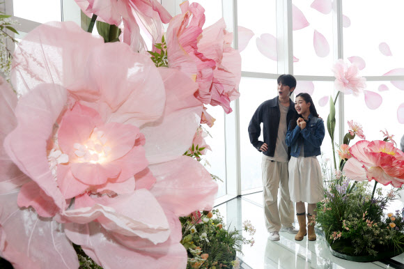 20일 서울 송파구 롯데월드타워 전망대 서울스카이에서 모델들이 플라워 체험형 공간 ‘블루밍 유니버스: 빅 플라워’를 즐기고 있다.  2025.5.20  연합뉴스