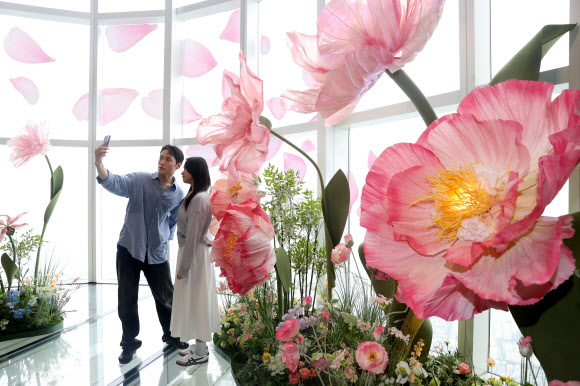 20일 서울 송파구 롯데월드타워 전망대 서울스카이에서 모델들이 플라워 체험형 공간 ‘블루밍 유니버스: 빅 플라워’를 즐기고 있다.  2025.5.20  연합뉴스