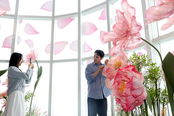 20일 서울 송파구 롯데월드타워 전망대 서울스카이에서 모델들이 플라워 체험형 공간 ‘블루밍 유니버스: 빅 플라워’를 즐기고 있다.  2025.5.20  연합뉴스