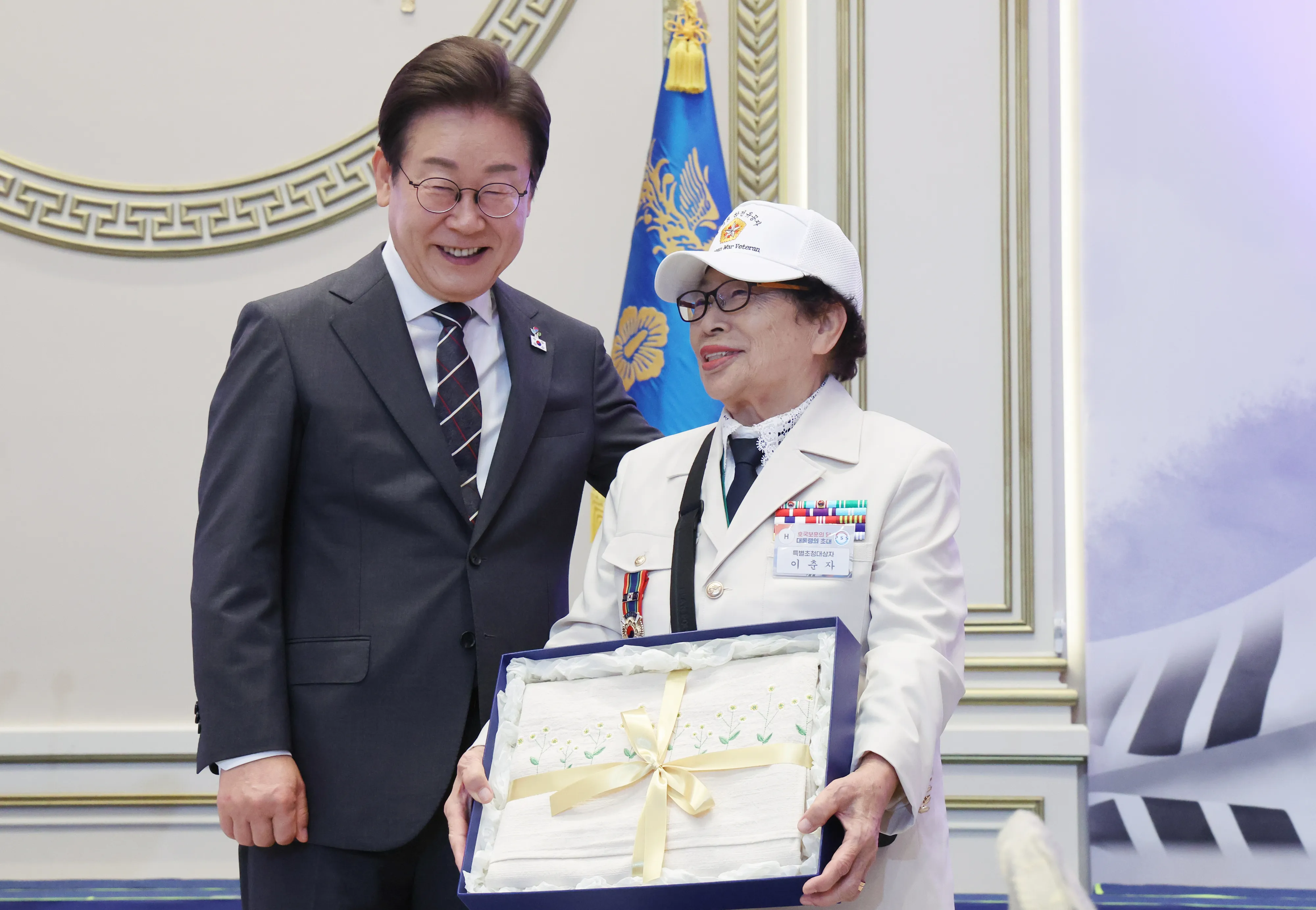 참전용사에게 선물 전달한 이재명 대통령  이재명 대통령이 27일 청와대 영빈관에서 열린 ‘호국보훈의 달, 대통령의 초대’ 행사에서 특별초청 대상자인 6·25전쟁 참전유공자 이춘자 참전용사에게 광목이불 선물을 전달 후 미소짓고 있다. 대통령실통신사진기자단 2025.06.27.