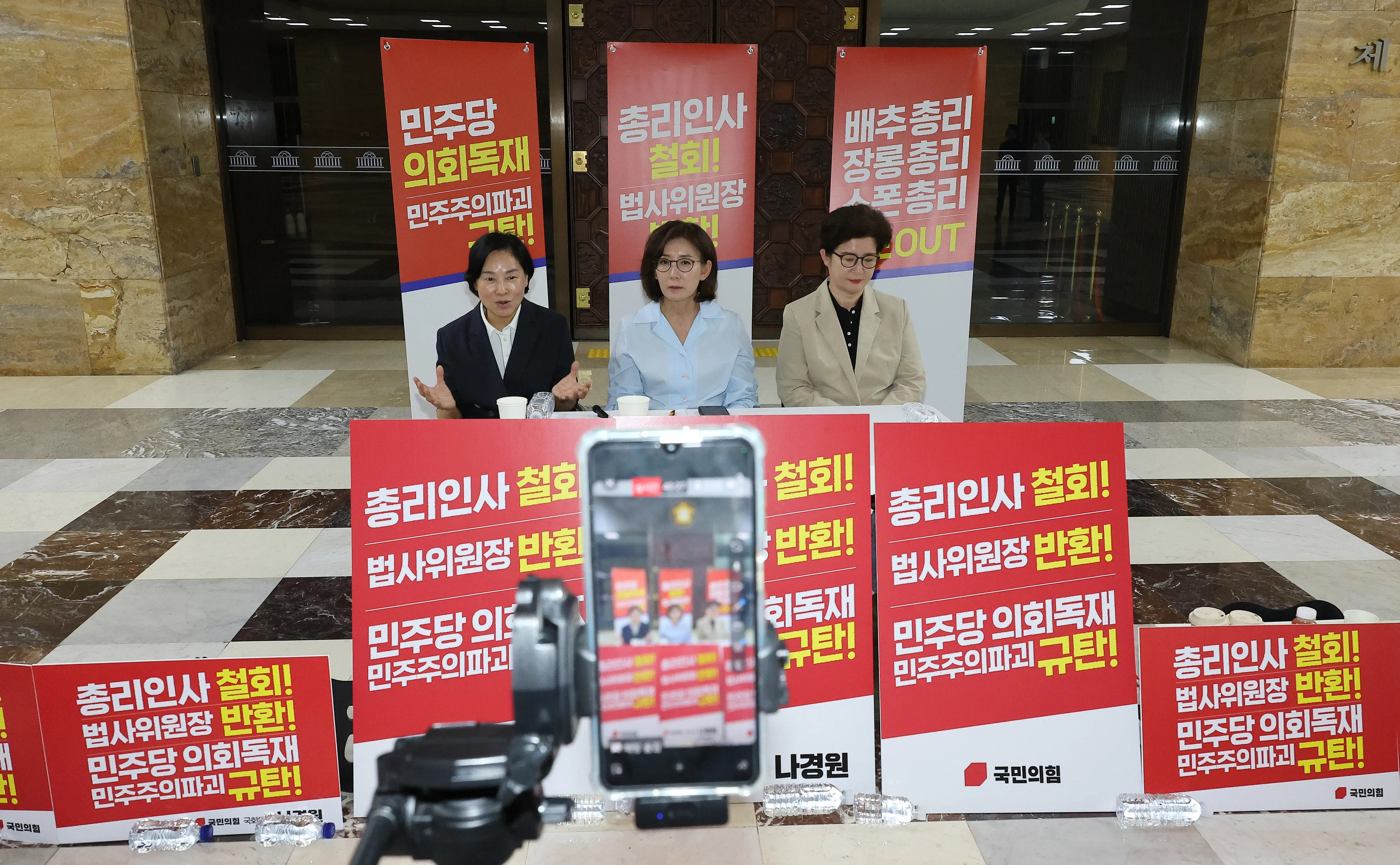 나경원 국회서 철야농성  나경원·서명옥·강선영 국민의힘 의원이 29일 국회 로텐더홀에서 김민석 국무총리 후보자 지명 철회와 민주당의 법제사법위원장직 반환을 촉구하는 철야농성 중 SNS로 라이브 방송을 하는 모습. 왼쪽부터 서 의원, 나 의원, 강 의원.
연합뉴스