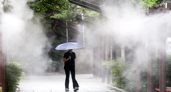 대구에 폭염경보가 발효 중인 30일 대구 중구 국채보상운동기념공원에 쿨링포그(안개형 냉각수)가 가동 중인 가운데 한 시민이 양산을 들고 이동하고 있다. 2025.6.30 연합뉴스