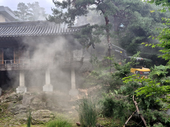 30일 서울 성북구 ‘성북동 별서(성락원)’ 내 송석정에서 화재가 발생, 화재진압을 위해 포크레인이 지붕을 부수고 있다. 2025.6.30  성북소방서 제공